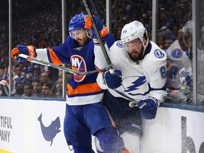 Nikita Kucherov of the Tampa Bay Lightning, being checked into the boards by Adam Pelech of the New York Islanders, is a question mark for their Game 7 showdown tonight at Amalie Arena..