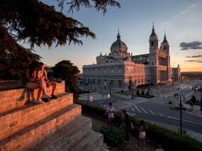 MADRID, SPAIN - JUNE 07: People sit near the Almudena Cathedral during sunset on June 07, 2021 in Madrid, Spain.