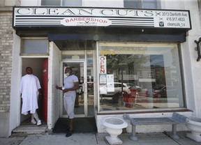 Inskip Redman (right), owner of Clean Cuts barber shop on Danforth Ave. west of Woodbine Ave., talks outside his shop before cutting the hair of one of his best clients and friends, John Robinson Jr. on his rear outside rooftop deck. JACK BOLAND/TORONTO SUN