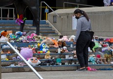 A woman pauses Thursday at the Calgary City Hall memorial to children who died at residential schools in Canada. Hundreds more unmarked graves have been discovered at a former residential school site in Saskatchewan.