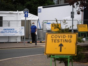 Workers wait to receive members of the public queue at a temporary COVID-19 testing centre set up a car park in Penrith in Cumbria, England, Monday, June 21, 2021, following an outbreak of a coronavirus variant of concern.