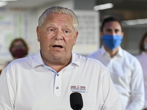 Ontario Premier Doug Ford speaks as Education Minister Stephen Lecce listens at Father Leo J Austin Catholic Secondary School in Whitby on July 30, 2020.