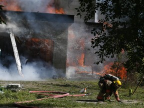 A firefighter drops the hose and leaps to safety as flaming timbers fall while battling a house fire on Beachview St. In Ajax on Tuesday, June 15, 2021.