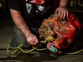 A man ties a rope to the head from a statue of Egerton Ryerson, considered one of the architect’s of Canada’s residential school system, before throwing it into Lake Ontario in Toronto, on June 6, 2021.