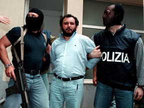 Anti-Mafia police wearing masks to hide their identity, escort top Mafia fugitive Giovani Brusca May 21 as he leaves Palermo's police headquarters to be taken to a maximum security prison.