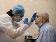 A medical worker wearing protective equipment takes a swab from a woman at a medical facility in Moscow on July 16, 2020.