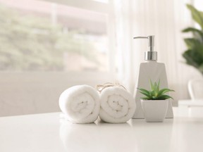 Soap dispenser and spa towel ,Roll up of white towels on white table with copy space,towels studio shot on white table Copy space