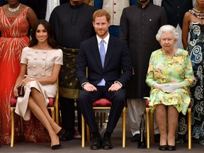Queen Elizabeth, Prince Harry and Meghan, the Duchess of Sussex pose for a picture with some of Queen's Young Leaders at a Buckingham Palace reception following the final Queen's Young Leaders Awards Ceremony, in London on June 26, 2018.