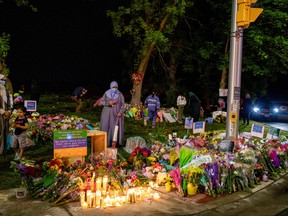 People gather at a makeshift memorial at the fatal crime scene where a man driving a pickup truck jumped the curb and ran over a Muslim family in what police say was a deliberately targeted anti-Islamic hate crime, in London, Ont., June 8, 2021.