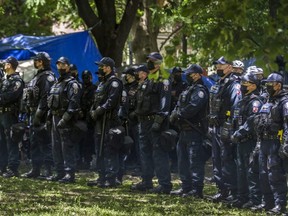 A column of police officers clears a homeless encampment at the northern side of Trinity Bellwoods Park in Toronto, Ont. on Tuesday June 22, 2021.