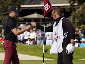 Mackenzie Hughes (left) fist bumps his caddie Jace Walker after finishing up his third round at the U.S. Open yesterday. The Dundas, Ont., native is tied for the lead with two other players at five-under par after shooting a three-under 68.