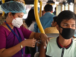 A health worker inoculates a labourer with the first dose of Covishield vaccine against COVID-19 in a passenger bus converted into a mobile vaccination centre at a wholesale market in Kolkata on June 3, 2021.