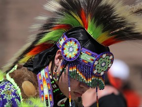 A First Nations dancer, part of a protest after the remains of 215 children were found at a residential school, prepares to march from the Ontario legislature in Toronto, June 6, 2021.