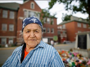 In this file photo Kamloops Indian Residential School survivor Evelyn Camille, 82, poses for a pictures next to a makeshift memorial at the former Kamloops Indian Residential School to honour the 215 children whose remains have been discovered buried near the facility, in Kamloops, B.C., on June 4, 2021.
