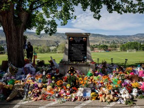 A makeshift memorial honoring the 215 children whose remains have been discovered buried near the facility surrounds a monument outside the former Kamloops Indian Residential School in Kamloops, B.C., on June 2, 2021.
