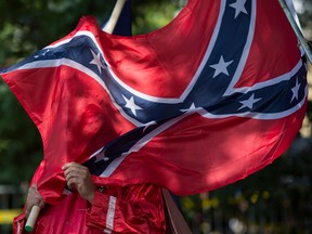 In this file photo taken on July 8, 2017 A member of the Ku Klux Klan holds a Confederate flag over his face during a rally, calling for the protection of Southern Confederate monuments, in Charlottesville, Va.