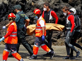 Rescue workers carry the body of a dead person after a boat with 46 migrants from the Maghreb region capsized in the beach of Orzola, in the Canary Island of Lanzarote, Spain June 18, 2021.