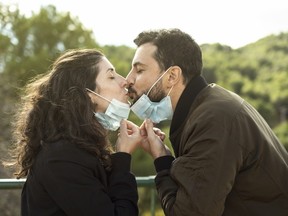 Couple kisses outdoors with a surgical mask. Outdoor portrait symbolizing pandemic love