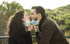 Couple kisses outdoors with a surgical mask. Outdoor portrait symbolizing pandemic love