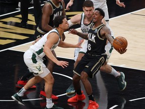 Lou Williams of the Atlanta Hawks draws a foul against Brook Lopez and Bryn Forbes of the Milwaukee Bucks during the second half in Game 4 of the Eastern Conference Finals at State Farm Arena on June 29, 2021 in Atlanta, Ga.