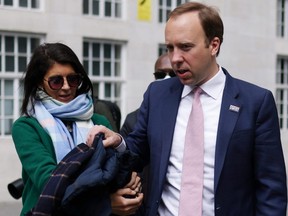 Britain's Health Secretary Matt Hancock hands his coat to his aide Gina Coladangelo before a TV interview outside the BBC's Broadcasting House in London, England, May 16, 2021.