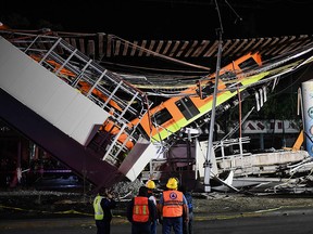 In this file photo taken on May 4, 2021, rescue workers gather at the site of a train accident after an elevated metro line collapsed in Mexico City.