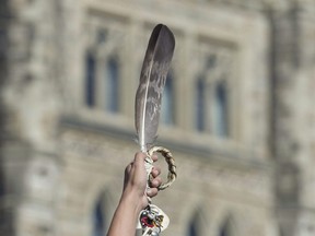 An eagle feather is held up during a rally for Missing and Murdered Indigenous Women and Girls on Parliament Hill in Ottawa, Tuesday Oct.  4, 2016.