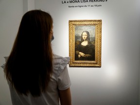 A woman looks at the Hekking "Mona Lisa", a reproduction of Leonardo Da Vinci's Mona Lisa, painted on canvas by an unknown artist from the 17th century and up for an online sale at Christie’s auction house in Paris, France, June 11, 2021.