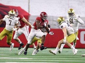 Alabama Crimson Tide running back Brian Robinson Jr. (4) runs against Notre Dame Fighting Irish linebacker Drew White (40) and linebacker Marist Liufau (35) during the Rose Bowl at AT&T Stadium in Arlington, Texas, Jan. 1, 2021.