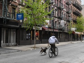 A person rides a bike with their dog past closed stores in New York City, April 29, 2020.
