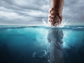 A hand reaches down into the water and saves someone drowning.