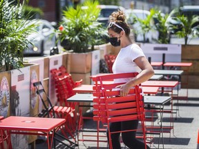 Virginia McIntosh co-owner of Breakwall BBQ, brings out the chairs in preparation for patio reopenings in Toronto.