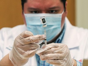 Walgreens health-care professional Luis S. Solano prepares a dose of the Pfizer-BioNTec vaccine against COVID-19 at the Victor Walchirk Apartments in Evanston, Ill., Feb. 22, 2021.