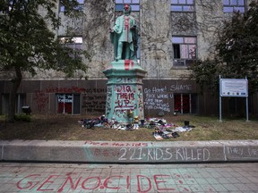 A statue of Egerton Ryerson is covered in paint and graffiti with shoes left at the base at Ryerson University in downtown Toronto on Tuesday June 1, 2021.