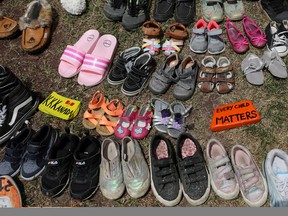 Children's shoes line the base of the defaced Ryerson University statue of Egerton Ryerson, considered an architect of Canada's residential indigenous school system, in Toronto June 2, 2021.