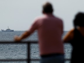 People watch as the Spanish vessel Angeles Alvarino carries out a search operation to try to locate a second missing girl and her father, near the coast of the Spanish island of Tenerife, Spain, June 11, 2021.