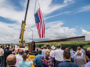 People listen to former president Donald Trump's address during a tour to an unfinished section of the border wall on June 30, 2021 in Pharr, Texas.