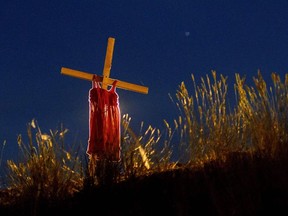 In this file photo taken on June 06, 2021, a child's dress is hung on a cross on the side of Highway 5, near the former Kamloops Indian Residential School, where the remains of 215 children were discovered buried near the facility, in Kamloops, Canada.
