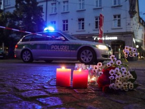 Flowers and candles in tribute to the victims of a deadly attack are seen on the street as police secures the city center in Wuerzburg, southern Germany on June 25, 2021. - A 24-year-old Somalian man killed three people on Friday, June 25, 2021 in an attack in the southern German city of Wuerzburg that also left several others injured, some of them seriously, police said.