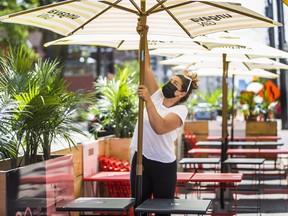 Virginia McIntosh co-owner of Breakwall BBQ, brings out the umbrellas for the CafeTO patio, the along Queen St. E, just west of Woodbine Ave., Toronto, Ont. on Thursday, June 10, 2021.