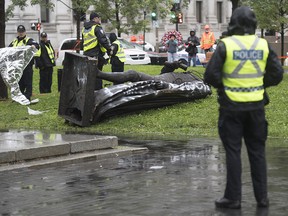 Police officers preserve the scene next to the statue of Sir John A. MacDonald after it was torn down following a demonstration in Montreal, Saturday, Aug. 29, 2020.