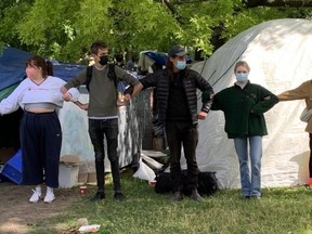 Activists link arms to prevent the removal of an encampment at Toronto's Trinity Bellwoods Park on Tuesday, June 22