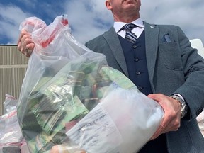 Supt. Steve Watt of Toronto Police with a sack of cash seized as part of Project Brisa on Tuesday, June 22 2021