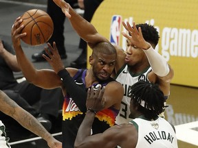 Chris Paul #3 of the Phoenix Suns is pressured by Giannis Antetokounmpo #34 and Jrue Holiday #21 of the Milwaukee Bucks during the second half in Game 1 of the NBA Finals