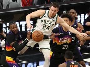 Pat Connaughton of the Milwaukee Bucks looes the ball against Jae Crowder (left) and Cameron Johnson of the Suns during the first half in Game 5 at the Footprint Center on July 17, 2021 in Phoenix.