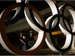 A woman wearing a face mask walks past Olympic rings on July 20, 2021 in Tokyo, Japan.