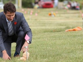 Prime Minister Justin Trudeau places a teddy bear at an unmarked grave on Cowessess First Nation, where a search had found 751 unmarked graves from the former Marieval Indian Residential School near Grayson, Saskatchewan, July 6, 2021.