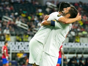 Canada's defender Steven Vitoria (R) lifts up midfielder Stephen Eustaquio (C) as they celebrates after scoring against Cost Rica during the Concacaf Gold Cup quarterfinal football match between Costa Rica and Canada at the AT&T Stadium in Arlington, Texas on July 25, 2021.