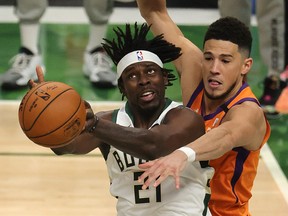 Jrue Holiday of the Milwaukee Bucks is defended by Devin Booker of the Phoenix Suns during the second half in Game 4  of the NBA Finals at Fiserv Forum on July 14, 2021 in Milwaukee, Wisc.