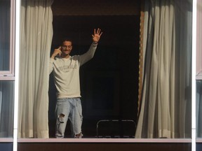 A man waves from the window of the Radisson Blu Hotel at Heathrow Airport after Britain introduced hotel quarantines for arrivals from a "red list" of 30 countries, in London, Feb. 15, 2021.